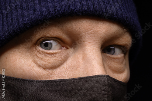 A middle-aged man in a black medical mask and a knitted hat. Close-up portrait.