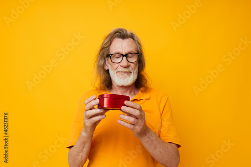 Wallpaper Mural Photo of retired old man yellow t-shirt and glasses posing heart-shaped box yellow background Torontodigital.ca