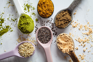Super food powders in spoons, white marble background.