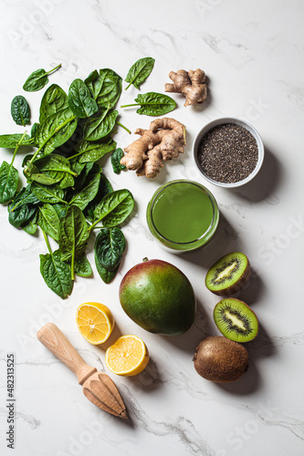 Green spinach and mango smoothie with ingredients on white marble background. Detox drinks concept.