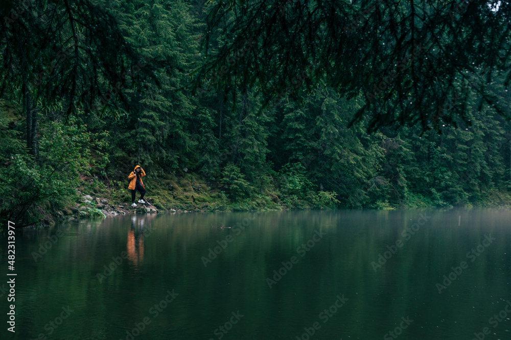 woman hiker in yellow raincoat at lake beach woman hiker in yellow raincoat at lake beach