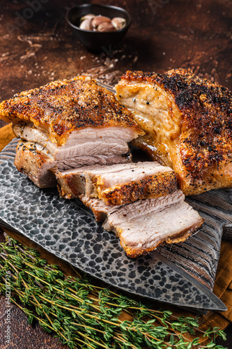 Roasted Pork belly bacon with crust on a wooden board. Dark background. Top view