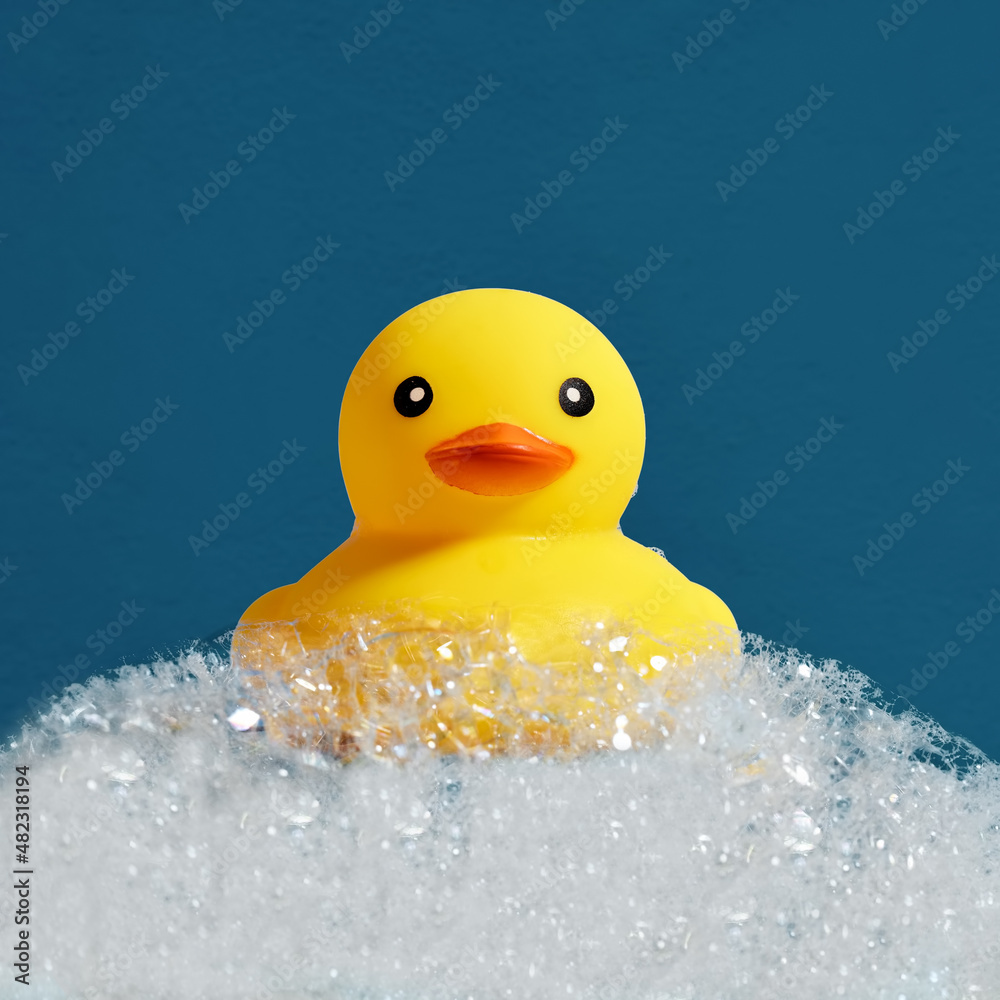 Yellow rubber duck toy floating on soap or shampoo bubble foam in the bath. Duckling in bubble bathtub with soapy foam. Yellow rubber duck toy floating on soap or shampoo bubble foam in the bath. Duckling in bubble bathtub with soapy foam.