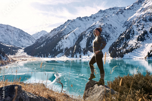 A woman walking near a frozen mountain lake
