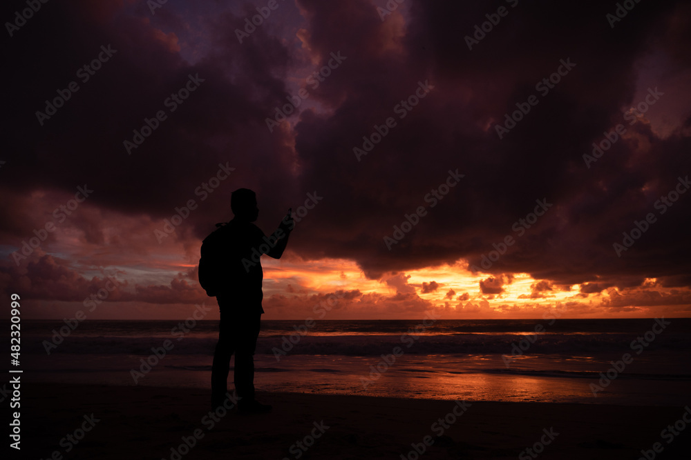 Silhouette of a traveler watching sunset at beach