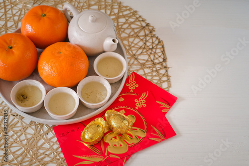 Chinese New Year festival concept. Mandarin oranges, red envelopes, gold ingots and tea pot with white background. Chinese character "fu" which stands for luck