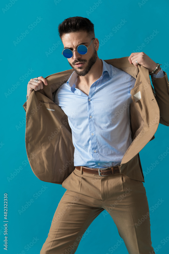 Obraz premium cool retro young man in suit with sunglasses adjusting jacket
