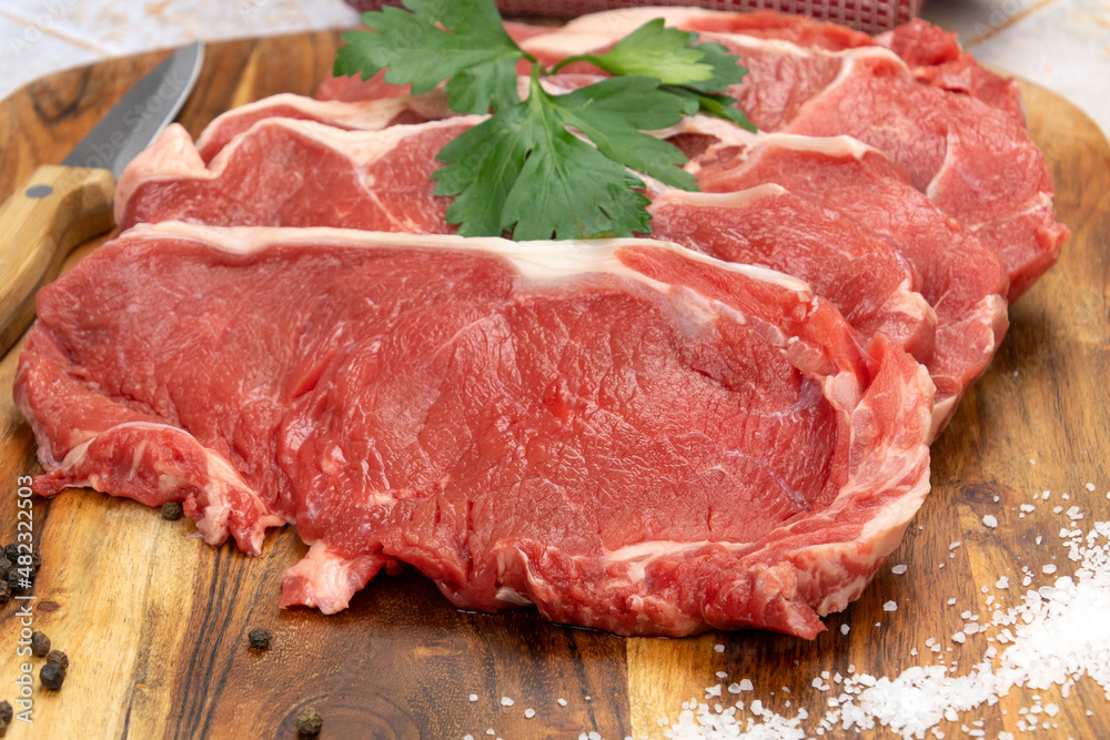  raw beef meat with spices and herbs on wooden cutting board