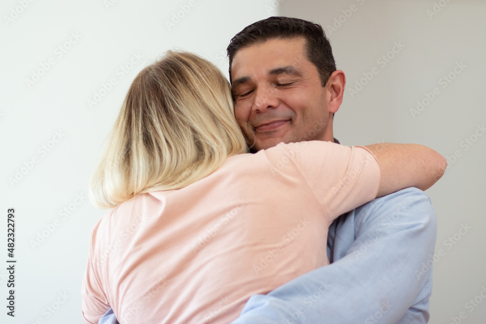 Happy loving husband hugging wife. Portrait of dark-haired mid adult man embracing fair-haired woman. Family, love concept Happy loving husband hugging wife. Portrait of dark-haired mid adult man embracing fair-haired woman. Family, love concept
