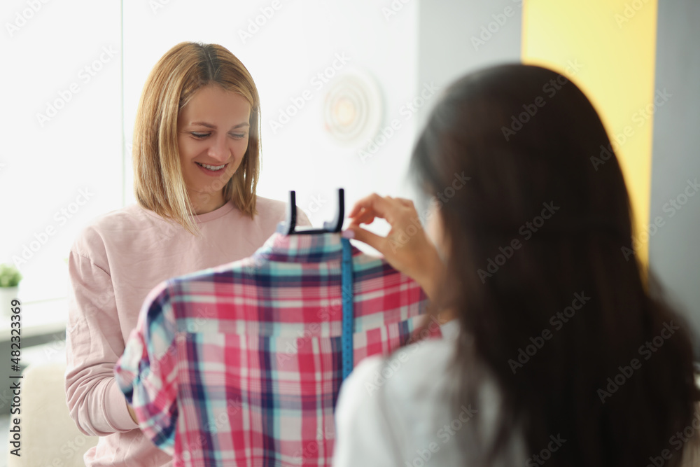 A woman seamstress shows a client a clothing A woman seamstress shows a client a clothing