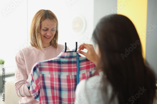 A woman seamstress shows a client a clothing