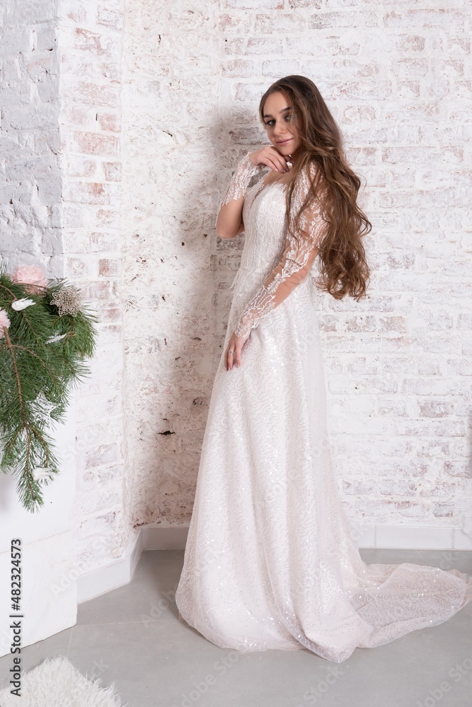 Fototapeta premium The bride in full growth, against the backdrop of a white brick wall.