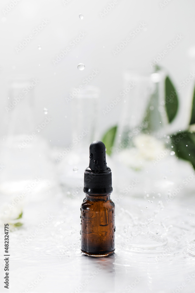 Glass dropper bottle with essential oil on wet table under falling down drops Glass dropper bottle with essential oil on wet table under falling down drops