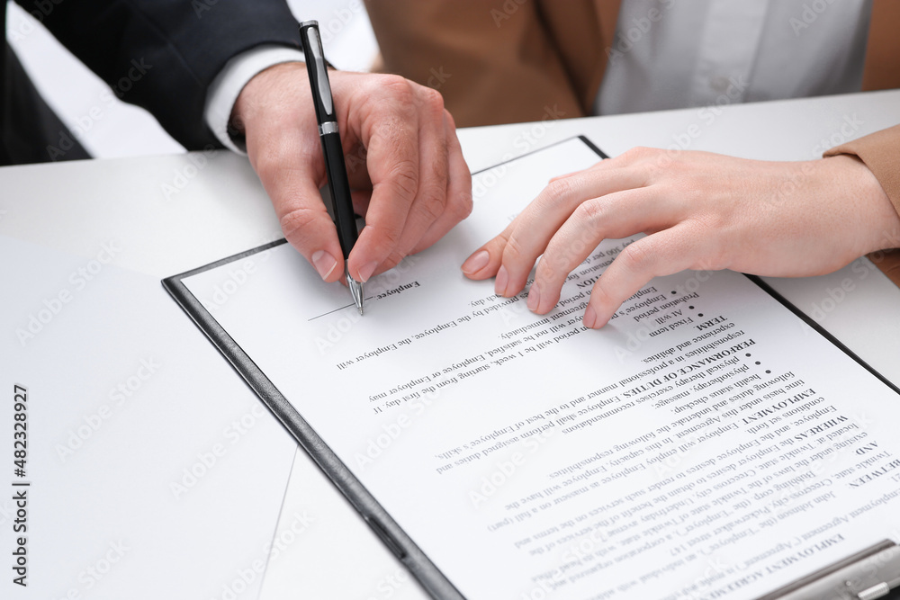Businesspeople signing contract at white table, closeup of hands