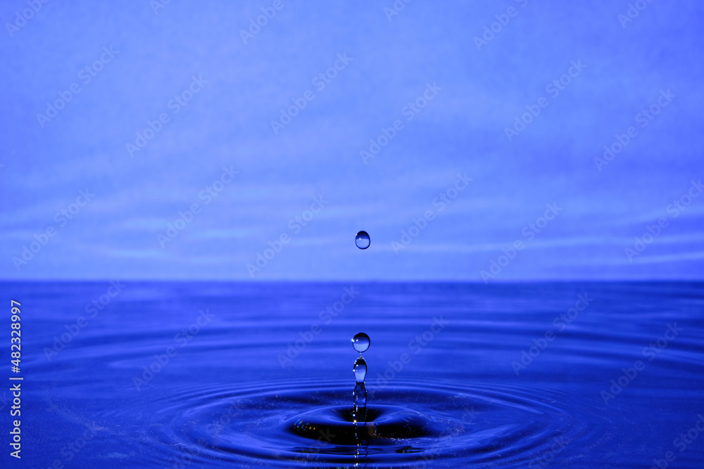 Splash water after drop falls.Lilac abstract background with drop in water. Splash water after drop falls.Lilac abstract background with drop in water.