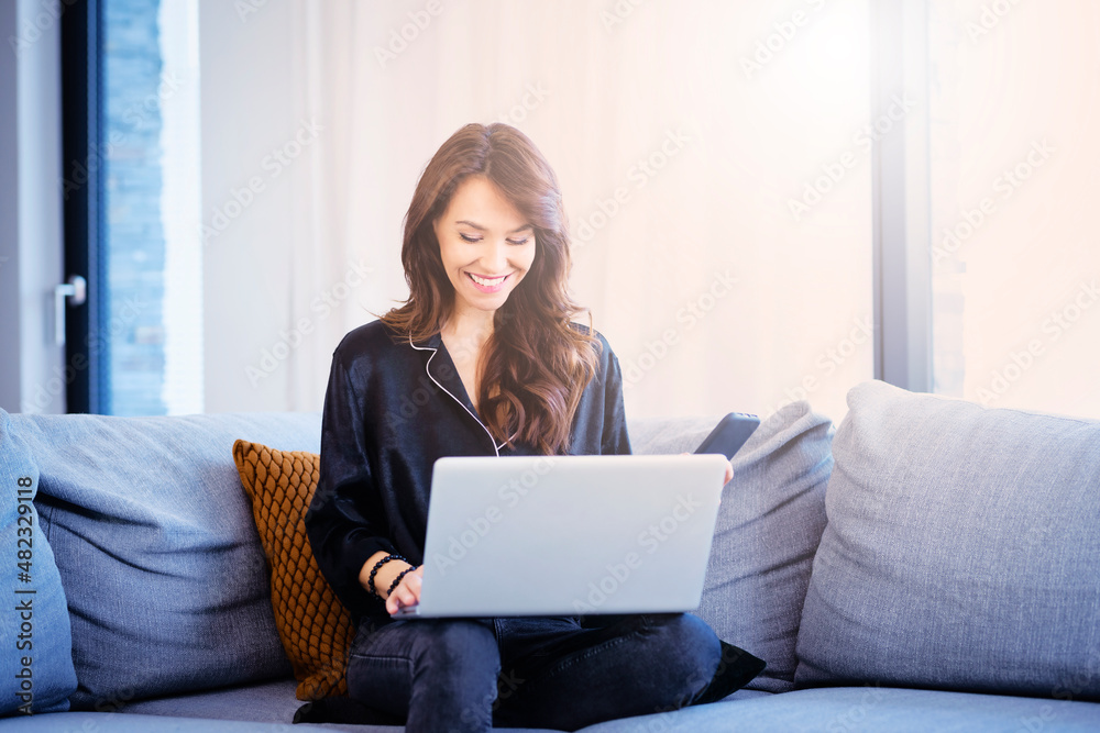 Cheerful middle aged woman relaxing on the couch while using her laptop Cheerful middle aged woman relaxing on the couch while using her laptop