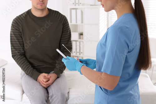 Doctor taking sample for STD testing from man in clinic, closeup photo
