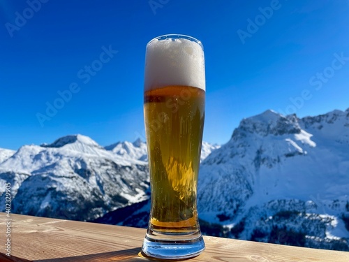 Apres ski in the Austrian Alps. Glass of wheat beer on wooden fence on a sunny day. Lech Zuers skiing resort, part of the Arlberg skiing area.