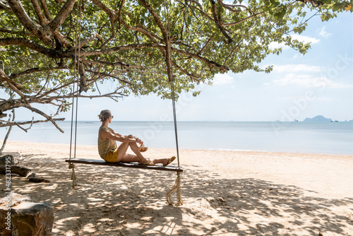 Woman sitting on swing at Ao Nang beach, Krabi Province, Thailand photo