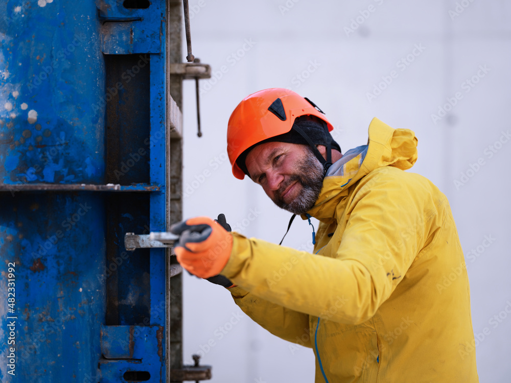 Worker with hardhat examining metal structure at construction Worker with hardhat examining metal structure at construction