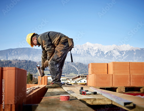 Bricklayer fixing bricks with glue holding caulk gun at construction site photo