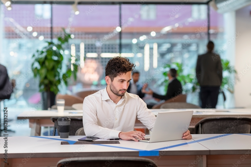 Businessman working over laptop at desk in office Businessman working over laptop at desk in office