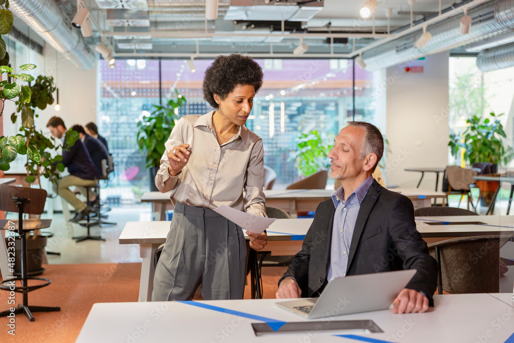 Employee showing paper document to manager in office Employee showing paper document to manager in office
