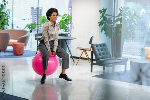 Manager bouncing on hopper ball in office