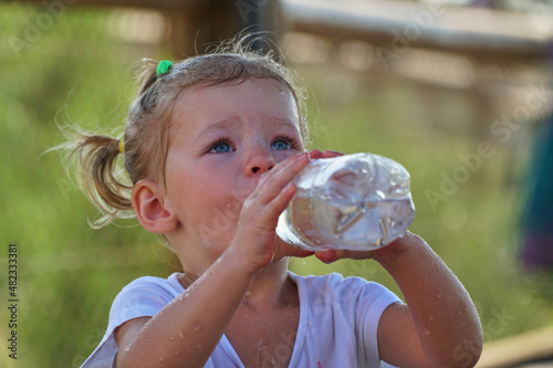 Happy Child drinks water. Little cute girl plays with a bottle of water splashes. Funny kids games. Healthy food for babies. High quality FullHD footage
