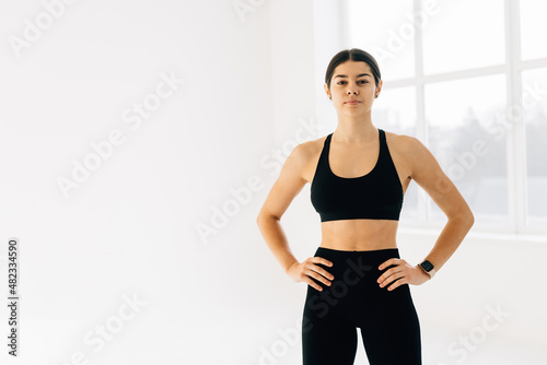 Attractive young adult in sportswear posing on white background. Young woman with perfect body posing in studio isolated over white background with copyspace.