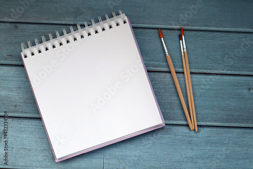 Art album and paint brashes on blue wooden boards. photo
