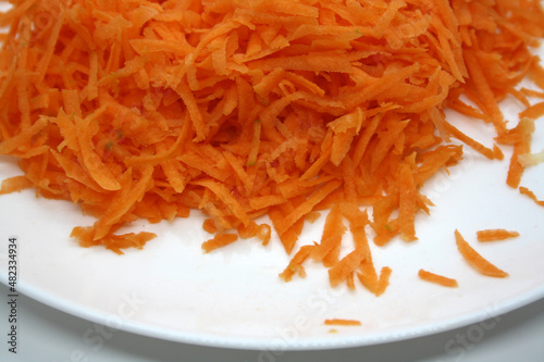Grated orange carrots on a white plate. Background.