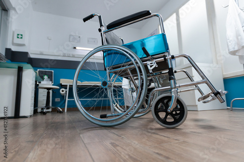 Empty doctor office with nobody in it having medical wheelchair for invalid patient. Hospital room equipped with modern professional instrument during clinical examination. Medicine concept