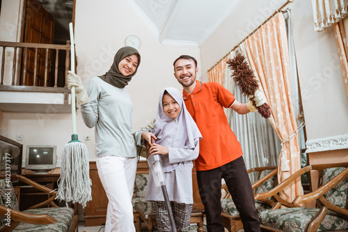 Happy Asian father, mother and daughter holding cleaning tools © Odua Images