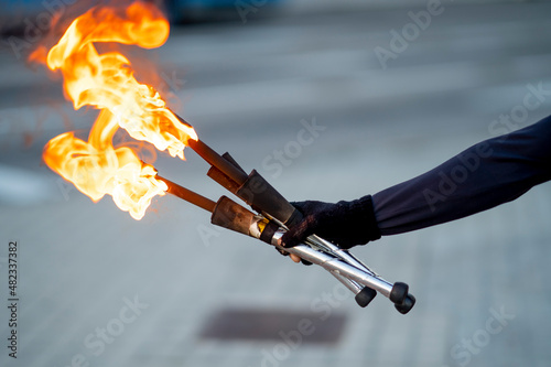 Hand of street artist holding flaming torches photo