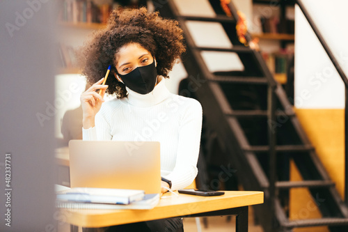 Businesswoman wearing protective mask working on laptop at office photo