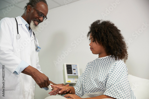 Doctor with pulse oximeter talking to patient at hospital photo