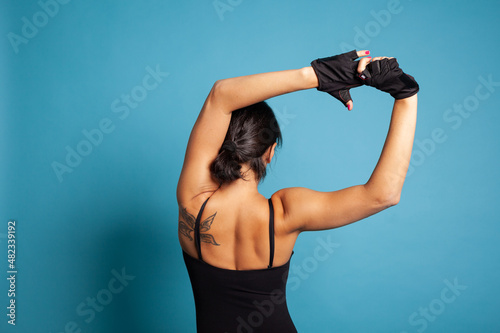 Back view of athletic trainer exercising gymnastic workout stretching body muscles working at healthy lifestyle. Active woman exercising aerobics posture practicing sport activity in studio © DC Studio