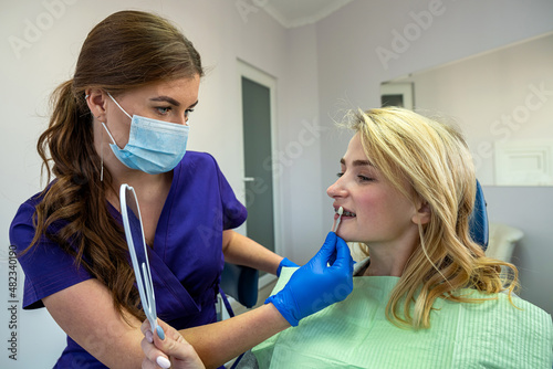  dentist woman in special clothes shows a palette of tooth colors for a female patient.