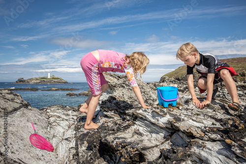 Children rock pooling with a lighthouse in the background.