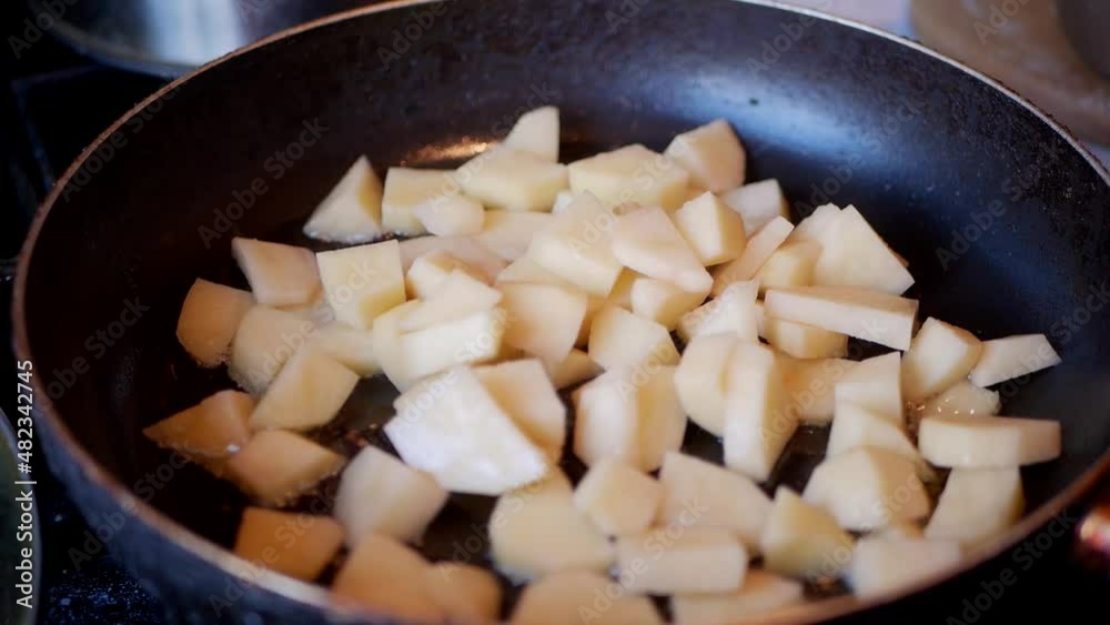diced potatoes are poured into a pan and fried in oil diced potatoes are poured into a pan and fried in oil