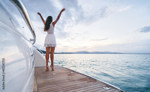 Luxury travel on the yacht. Young woman enjoying the sunset on boat deck sailing the sea. © luengo_ua