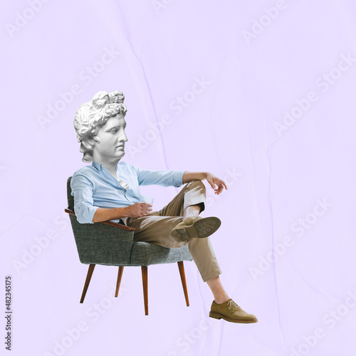 Obraz na płótnie Male model wearing retro clothing headed of ancient statue head sitting in armchair