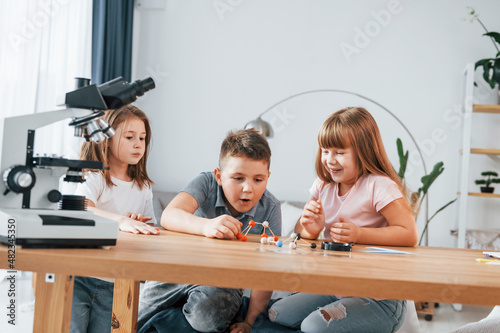 Using microscope. Kids having fun in the domestic room at daytime together