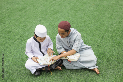 A senior Islamic boarding school student is guiding his colleague in the courtyard of the mosque photo