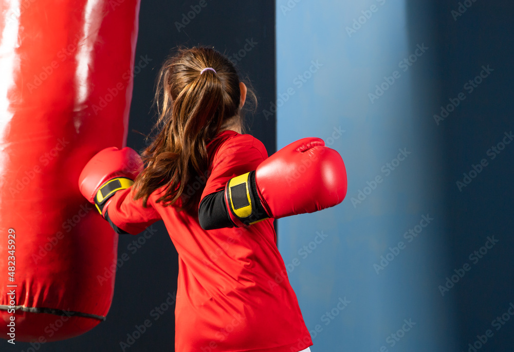 A girl in boxing gloves hits a punching bag