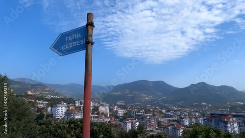 Signpost with Fatih Caddesi written on it in a Turkish city. A small village is in the background. View of blue sky and mountains in Turkey. photo
