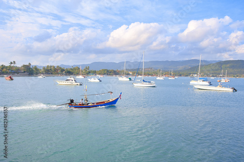 Beautiful landscape with white yachts and traditional thai longtail boat in blue lagoon.