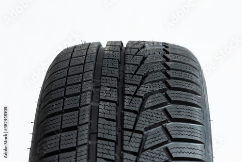 Detailed close-up view of winter tire isolated on white background. Regular pattern on rubber wheels cut out on blank. Concept of traction on roads in wintertime.