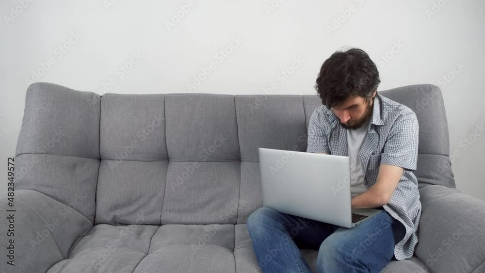 Handicapped Disabled man with amputated two stump hands working typing on laptop at home office sitting on sofa. Problem adaptation to life people with disabilities. Independent Invalid person. Handicapped Disabled man with amputated two stump hands working typing on laptop at home office sitting on sofa. Problem adaptation to life people with disabilities. Independent Invalid person.